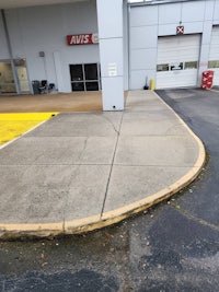 a parking lot with a concrete curb and a yellow sign