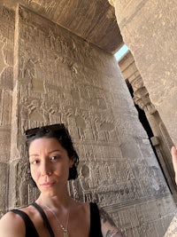 a woman taking a selfie in front of a stone wall