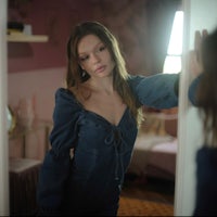 a woman in a blue dress standing in front of a mirror