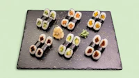 sushi on a black slate plate on a green background