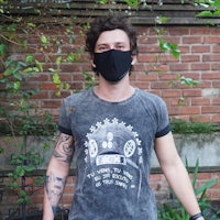 a man wearing a face mask in front of a brick wall