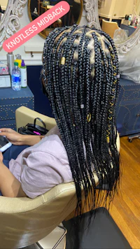 a woman sitting in a chair with braids in her hair