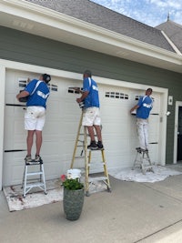 three men painting a white garage door