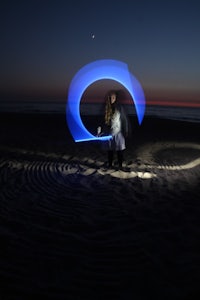 a person standing on the beach with a light saber