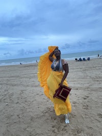 a woman in a yellow dress standing on the beach
