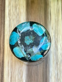 a black and turquoise cabochon on a wooden table