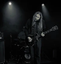a black and white photo of a man with long hair playing a guitar