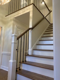 a staircase in a home with white railings and wood floors