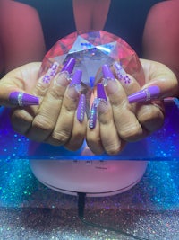 a woman with purple nails holding a crystal ball