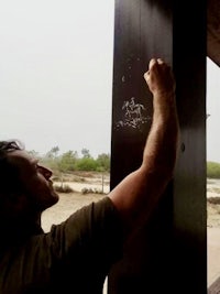 a man writing on the side of a wooden fence