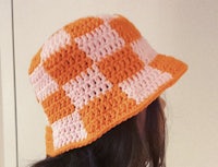 a woman wearing a crocheted orange and white bucket hat