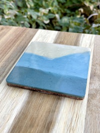 a blue and white ceramic coaster on a wooden table
