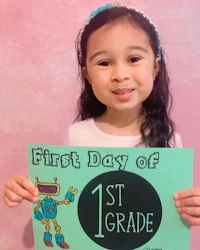 a girl holding a sign that says first day of 1st grade