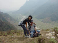 two people posing on top of a mountain with a valley in the background