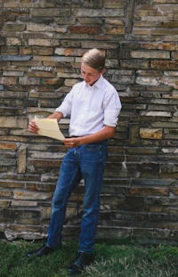 a man standing next to a stone wall holding a paper