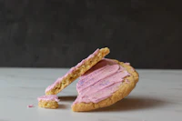 a pink frosted cookie with a bite taken out of it