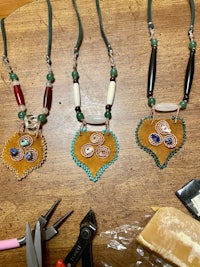 three necklaces with beads and scissors on a table