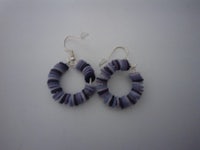 a pair of purple and black hoop earrings on a white surface