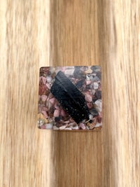 a black and pink quartz ring on top of a wooden surface