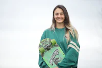 a young woman holding a green skateboard