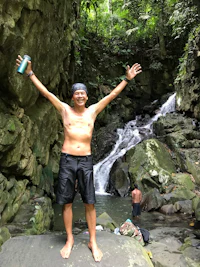 a man standing in front of a waterfall with his arms outstretched