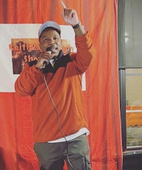 a man speaking into a microphone in front of a red curtain