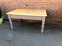 a grey table with a wooden top in front of a brick wall
