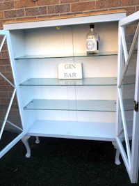 a white gin cabinet with a glass door