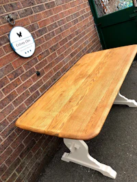 a wooden table with a white top and a brick wall behind it