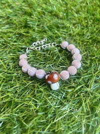 a bracelet with a pink and white bead and a silver chain
