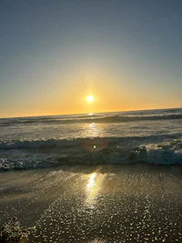 the sun is setting over the ocean in california