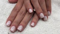 a woman's hands with white nails on a towel
