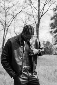 a man in a leather jacket standing in a field