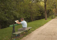 a man sitting on a park bench reading a map
