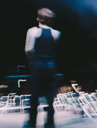 a man in a black tank top standing on a stage at night