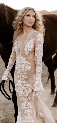 a woman in a white dress standing next to a horse