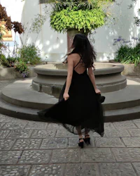 a woman in a black dress walking in a courtyard