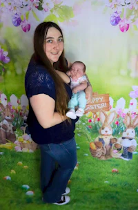 a woman holding a baby in front of an easter backdrop