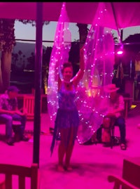 a woman in a blue dress is holding a light up umbrella