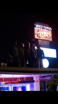 a group of people standing in front of a neon sign