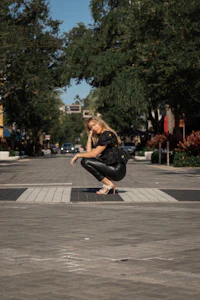 a woman crouching down in the middle of the street
