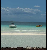 two boats in the water near a sandy beach