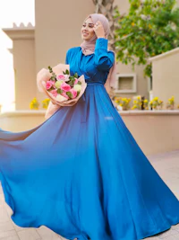 a muslim woman in a blue dress holding a bouquet of flowers
