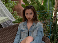 a girl in a denim jacket sitting on a wicker chair