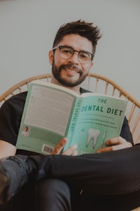 a man sitting in a chair reading a book about the dental diet