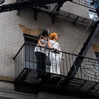 two women standing on a balcony