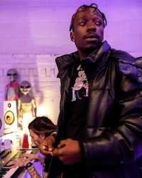 a man in a black jacket standing next to a keyboard