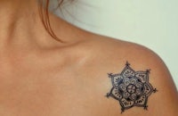 a woman with a black mandala tattoo on her shoulder