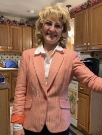 a woman in a pink blazer standing in a kitchen