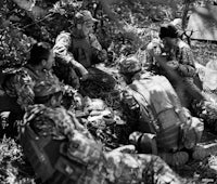 a group of soldiers are sitting in the woods